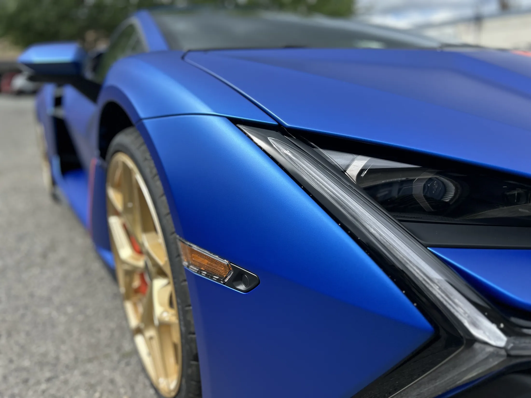 Close detail of a satin-blue Lamborghini Revuelto, bronze wheel and refinished paint by Jonathan Crespo.